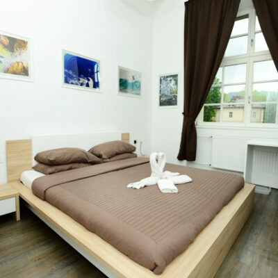 Double Room at Galeria Rooms - a cosy bedroom with a comfortable bed, photographs bove the bed, and a large window.